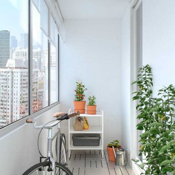 Ministerio JONAXEL white metal shelf holding orange plant pots, ideal for small spaces, fits neatly between large windows.