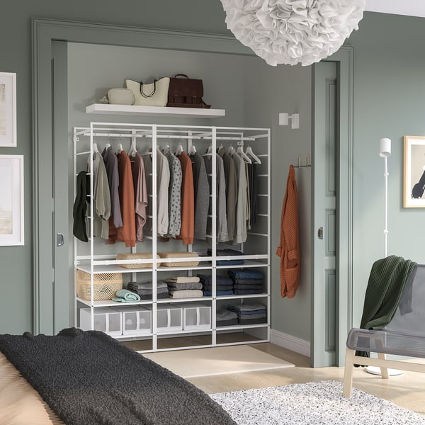 White metal storage unit with shelves & rails, holds clothes & fits between doors.