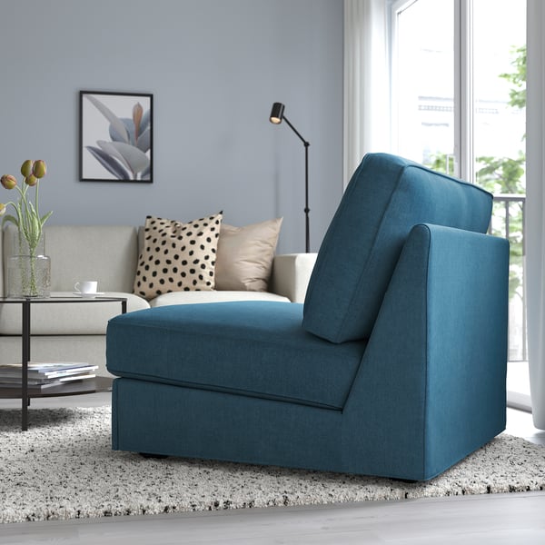 Blue sofa-bed in living room with floor lamp, coffee table, and large window.