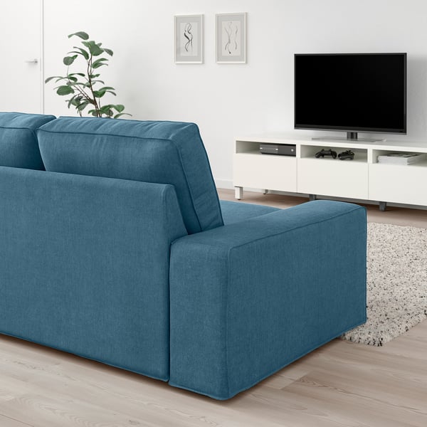 Modern living room with KIVIK blue sofa, flat-screen tv, and plant.