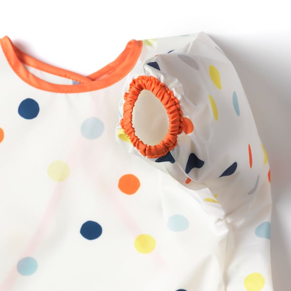 Vibrant kids bib with orange trim & colourful polka dots offers adjustable comfort & easy cleaning.
