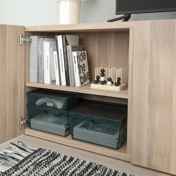 Clear storage boxes in light wooden cabinet, one holding books, the other storing paper items, ideal for organising and protecting contents.