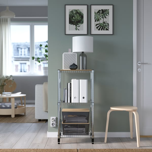 Modern living room with KUGGIS box on metal rack. Green walls, white lamp, leaf pictures. Perfect for organising.