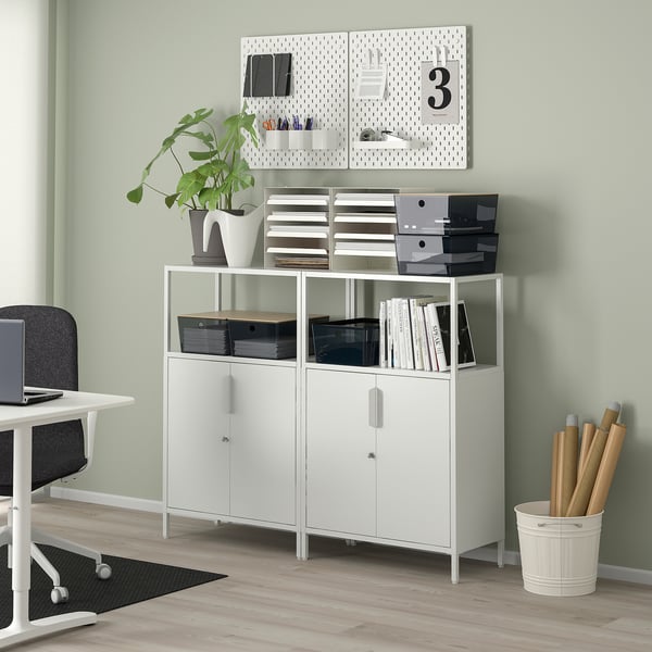 Office corner with KUGGIS boxes, plant, and pegboard on wooden floor.