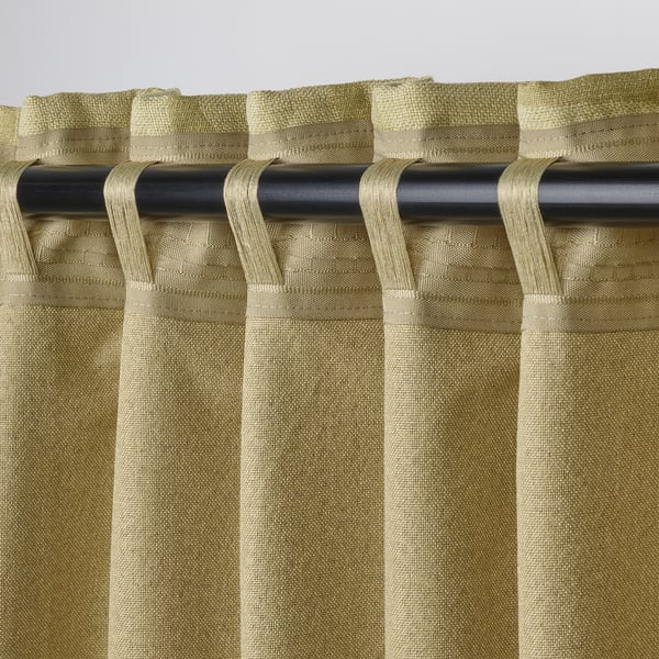 Green jacquard block-out curtains with tabs hang on black rod, providing light control and decor.