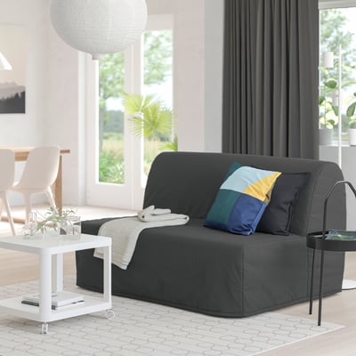 Modern living room with black LYCKSELE HÅVET sofa-bed, colourful pillow, white side table, and large window.