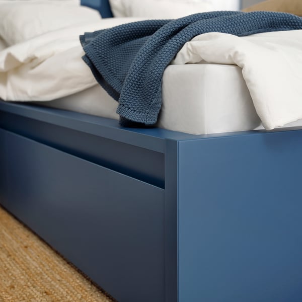 Stylish blue MALM bed with drawer, clean lines, quality finish, soft blankets, cosy ambiance.