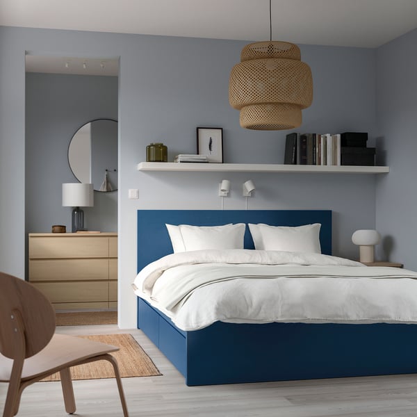 Modern blue MALM bed with storage, bookshelf, mirror, dresser, chairs, and rug.