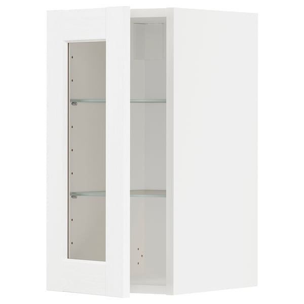 A white ikea METOD kitchen cabinet with glass doors and shelves.