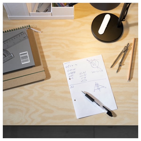 Desk with light wood top, notebook, pen, compass, calculator.