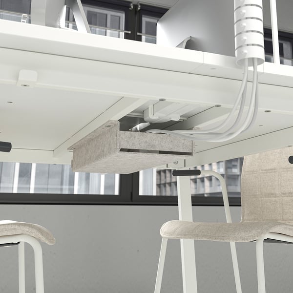 Under-table cable management: white system organising wires under desk.
