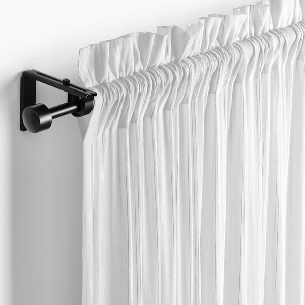 White sheer curtains with a slot heading hang from a black curtain rod, allowing light to philtre through and providing privacy.