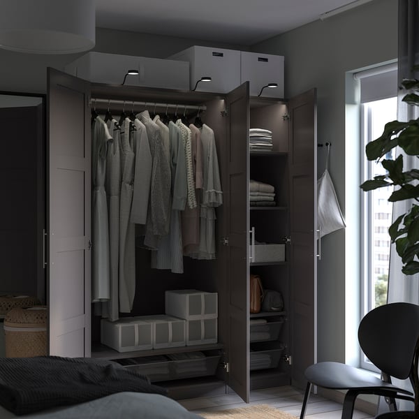 An open dark brown PAX wardrobe with clothes and organiser boxes.