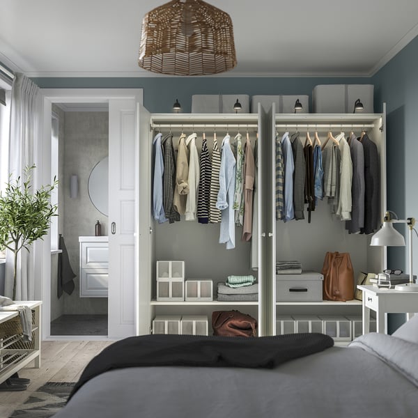 Modern bedroom with PAX wardrobe, clothes, shelves, and storage. Soft-close hinges, adjustable feet. Dark blanket bed, bathroom door.