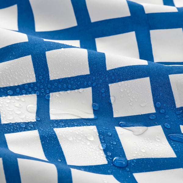 Blue and white grid-patterned tablecloth with water droplets, showcasing its water-repellent quality.