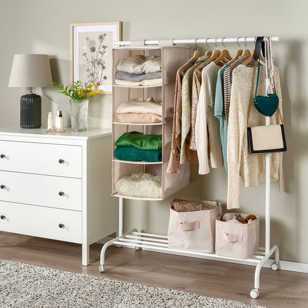 Hanging storage organiser, PURRPINGLA, with multiple compartments for clothes, next to a white dresser.