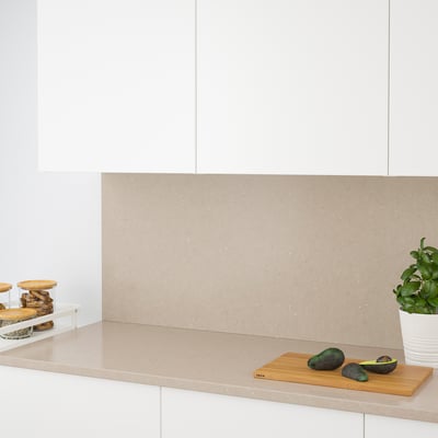 Beige quartz kitchen counter with avocados and plant.