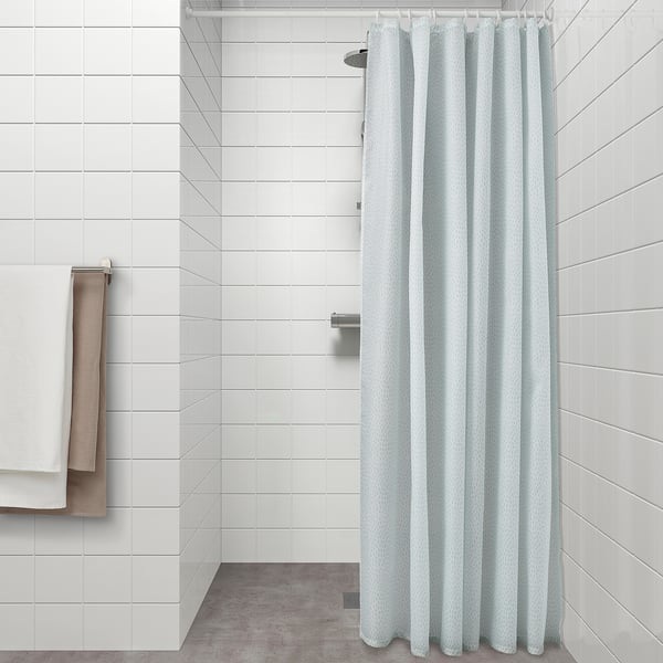 Light blue patterned shower curtain hangs neatly, dividing modern bathroom space.