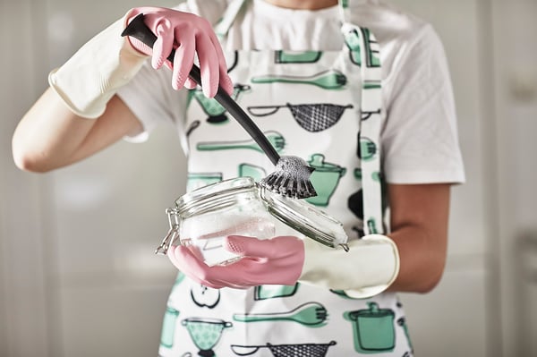 Chef in apron, gloves, adding powder, spraying.