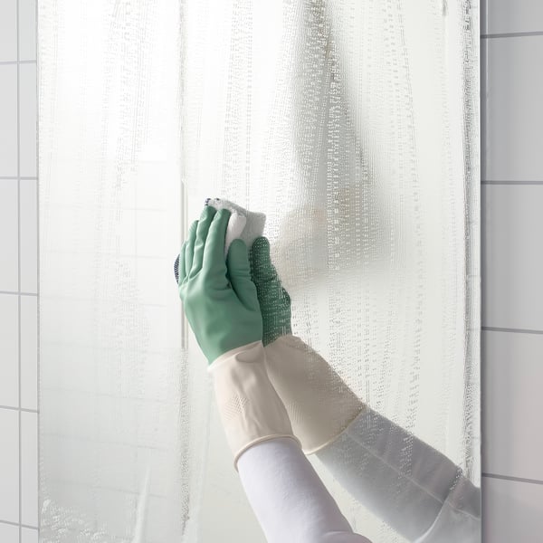 A person wearing dish gloves cleans a kitchen surface with a cloth. Gloves provide grip for better scrubbing.