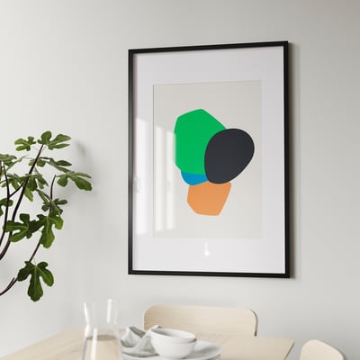 Framed abstract art print hangs on wall above wooden dining table with chairs, showcasing versatility in modern home decor.