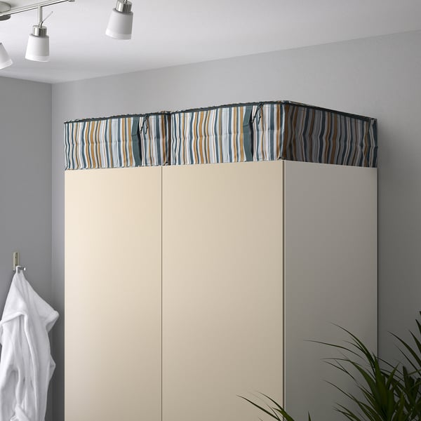 Closet with striped top, white doors, hanging towels, and potted plant.