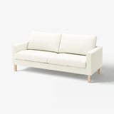 The SALTSJÖBADEN sofa, a white couch with a slim, modern design. It has wooden legs and is upholstered in cotton fabric.