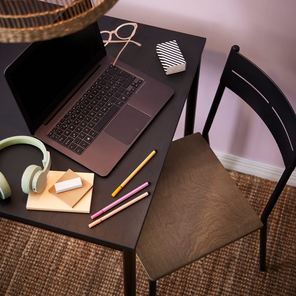 Modern black study desk with open laptop, headphones, notepads, and pens. Sleek and functional design, perfect for work or study.