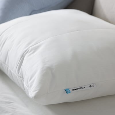 A white SENAPSMOTT pillow with synthetic filling. Its rectangular, offering support for side or back sleepers.