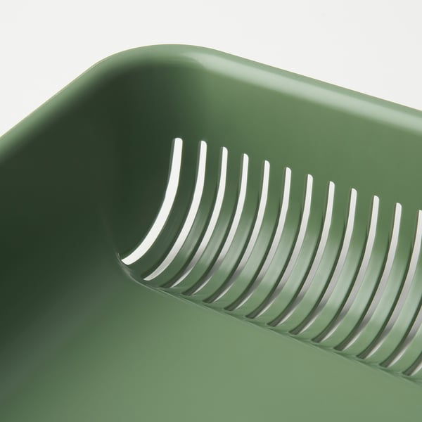 Green plastic strainer with multiple slits for draining food waste, designed for kitchen use.