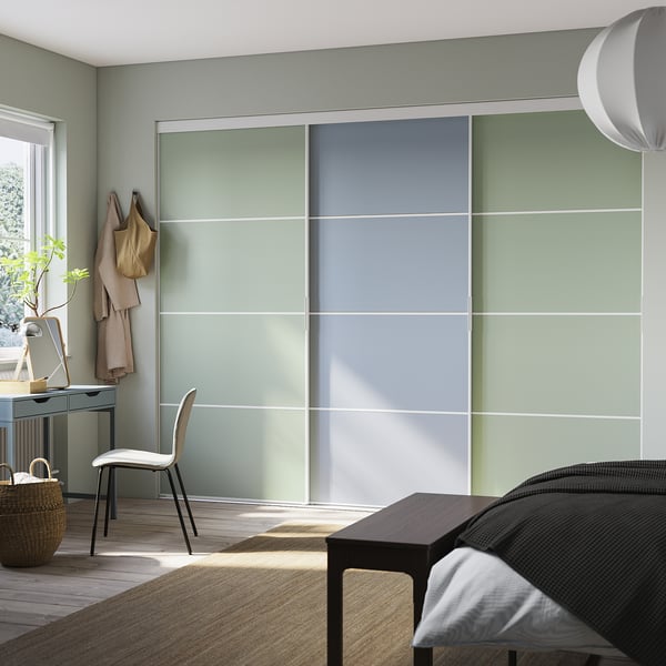 Modern bedroom with light green sliding closet doors, a white chair, and a wooden floor.