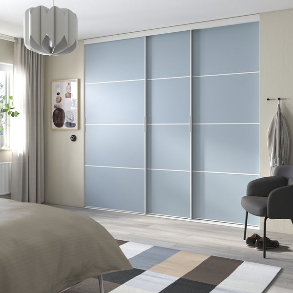 Modern bedroom with light blue sliding closet doors, a grey rug, and a beige comforter on the bed.