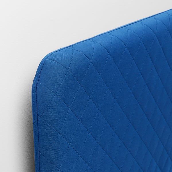 Close-up of a blue quilted bed frame corner, showcasing its detailed stitching and soft, vibrant material.