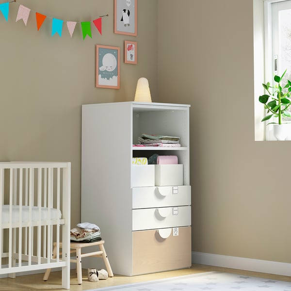 Nursery corner with white SMÅSTAD storage unit, crib, stool, decorations.