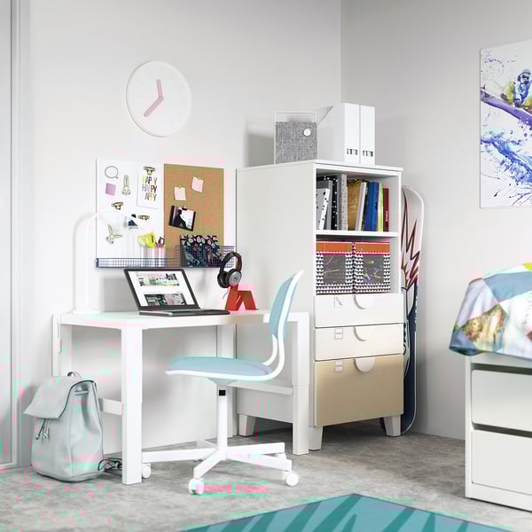 Childrens white study area with a desk, chair, laptop, backpack, and bookcase. A colourful pinboard and storage drawers.