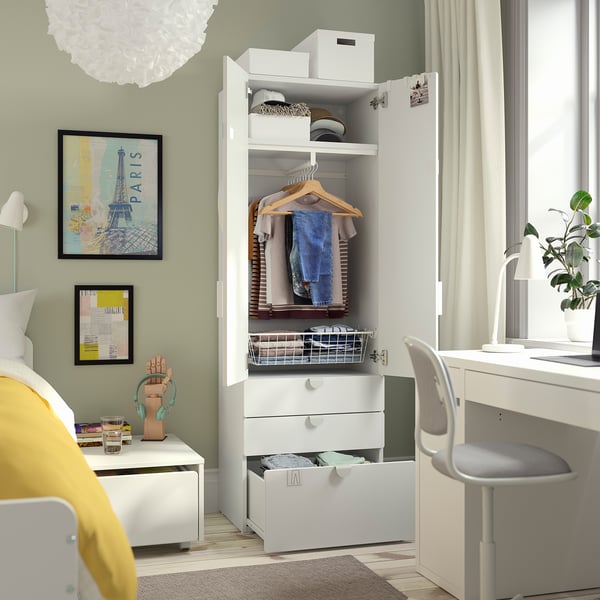 Bedroom with open white SMÅSTAD wardrobe displaying clothes, shelves, and organised storage solutions.