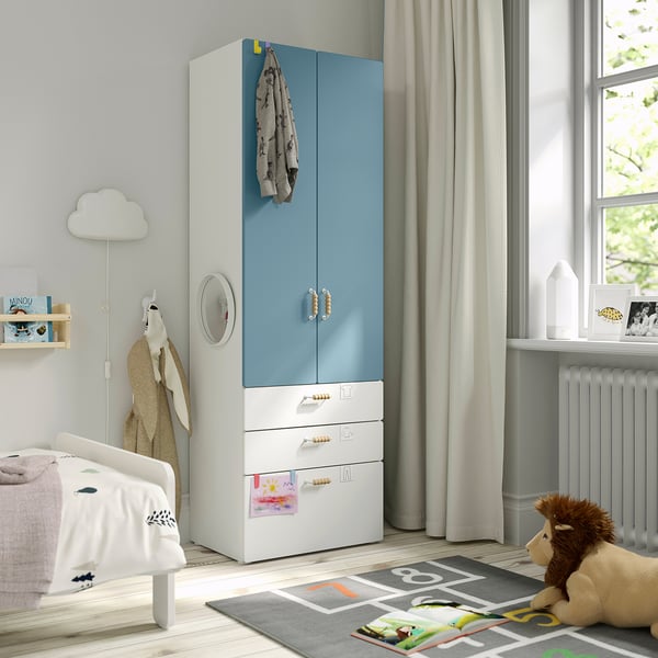 Kids room with blue-white SMÅSTAD wardrobe, drawers, cabinet, teddy bear, play mat, small bed.