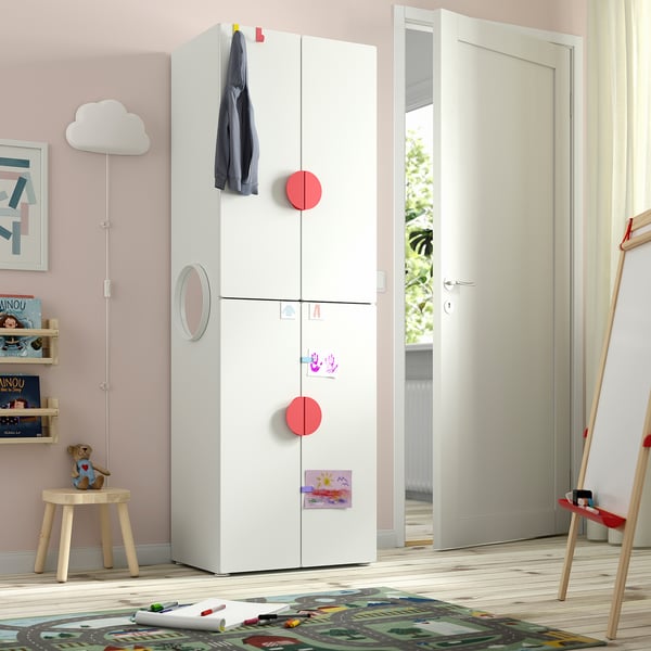 White SMÅSTAD wardrobe in childs room with red hooks, jacket, and nearby chest & bookshelf.