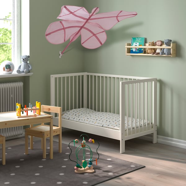 Kids room with butterfly bed, sage walls, toy table, rug, mobile.