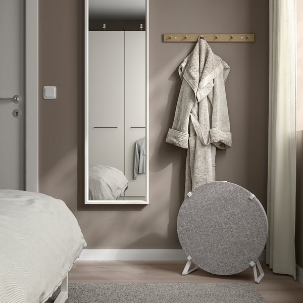 Minimalist bedroom with grey walls, wooden floor, white wardrobe, mirror, STARKVIND air purifier, robe hook, and bed.