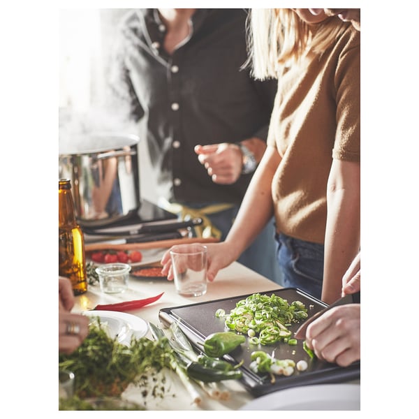 Two people chopping veggies on SYSSELSÄTTA board, surrounded by ingredients.