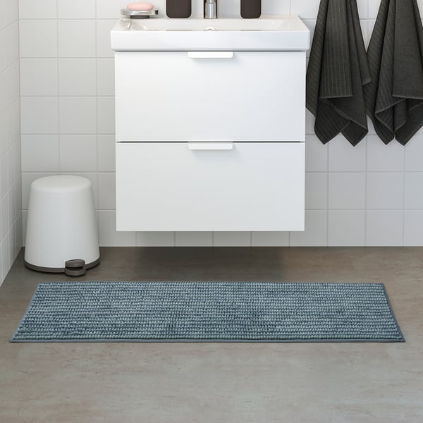 Modern bathroom with a white cabinet and sink, black towels, TOFTBO blue bath mat on the floor.