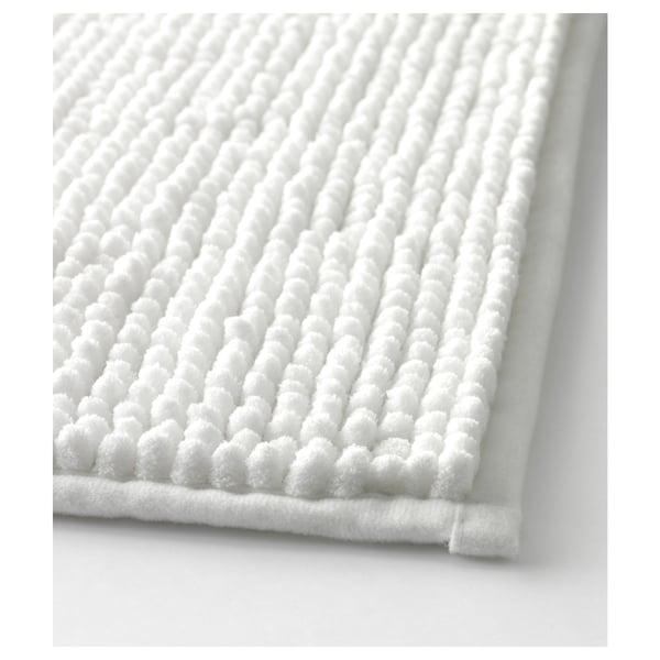 Close-up of plush, white textured bath mat with raised, soft dots.