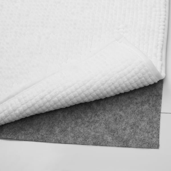 Close-up of a white textured bath rug, soft and fluffy microfiber material.