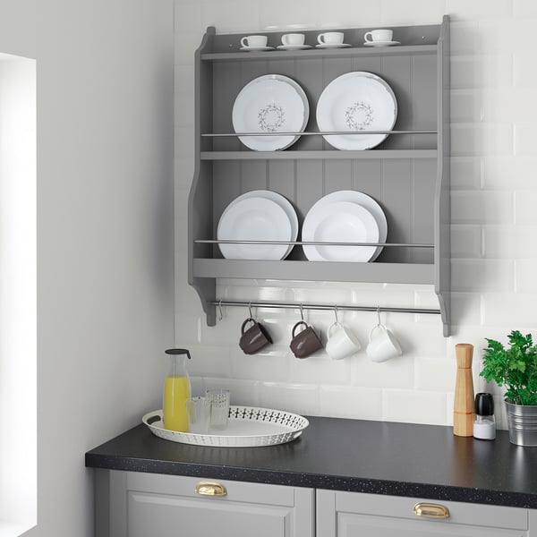 Modern kitchen grey TORNVIKEN wall shelf. Displays white dishes, mugs, and plants. Black counter with gold accents.