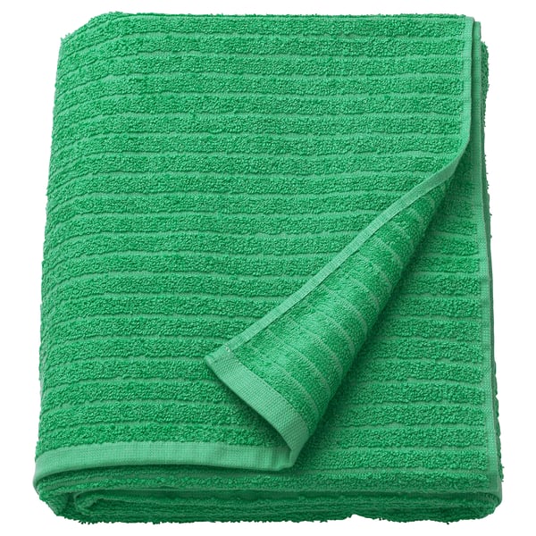 Bright green VÅGSJÖN towel, folded neatly, showcasing soft, textured terry cloth, pure cotton material.