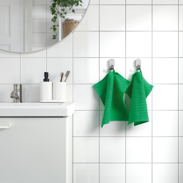 Green towel on hooks by white sink