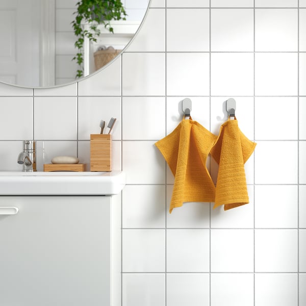 Golden towel on hooks in white-tiled bathroom, soft, absorbent cotton.