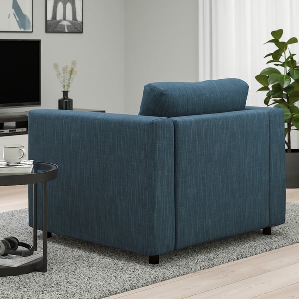 Blue upholstered armchair in modern living room with wooden floor and decor.