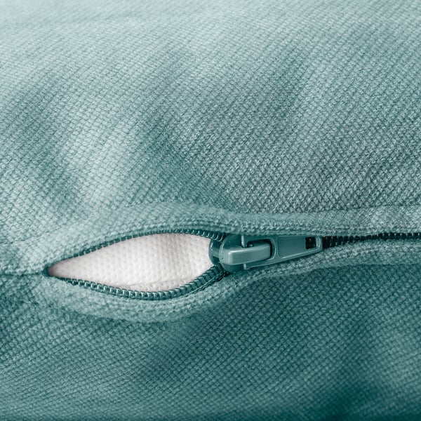 Close-up of high-quality zip on soft, textured green fabric, part of a comfortable sofa.